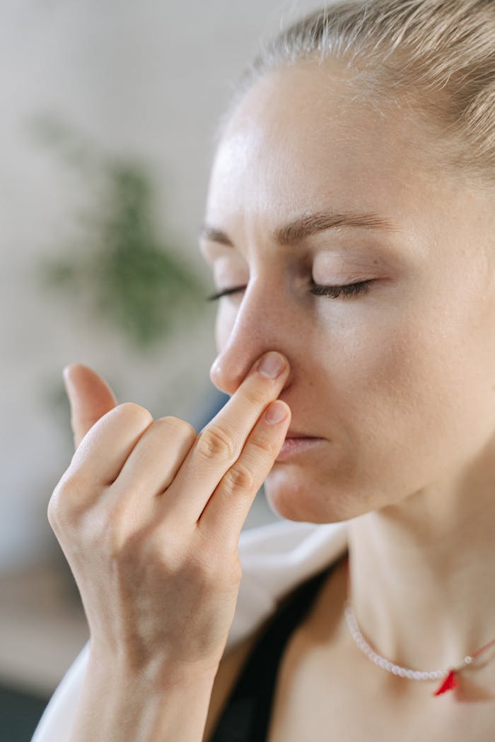 Close-up of a woman doing a breathing exercise with eyes closed indoors.